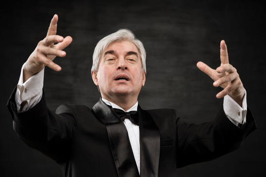 Closeup portrait of male orchestra conductor directing with his